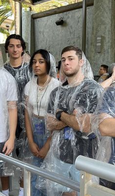 several people in plastic bags standing on a balcony