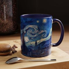 a blue coffee mug sitting on top of a wooden cutting board next to a spoon