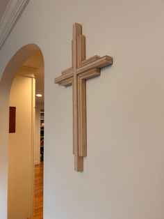 a wooden cross mounted to the side of a white wall next to a doorway in a house