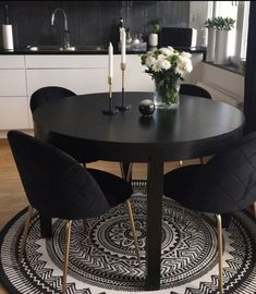 a round table with four black chairs around it in a room that has white and black decor on the floor