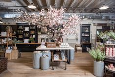 the inside of a store with lots of flowers in vases and plants on tables