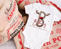 Featuring this limited edition artwork, your little one's initial is displayed in this Reindeer font with antlers and personalised with their name! A beautiful First Christmas Keepsake. Our designs are printed 'Direct to Garment' for long lasting results. Your design is printed onto 100% cotton super soft garments, which is the perfect combination for your baby's delicate skin, keeping them soft, warm and irritation-free! This stunning design can be printed on your choice of; 1. Babygrow (romper) - White, Long Sleeve/Legs and Footed - Available from Newborn up to 12 months 2. Vest (Bodysuit) - White, Short Sleeve with Poppers - Available from Newborn up to 24 months 3. Bib - White, One Size Available Please ensure you check size guide prior to ordering for the correct size. Christmas Baby Vest, First Christmas Keepsake, Bodysuit White, Christmas Keepsakes, Baby Vest, Baby Outfit