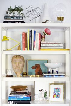 a bookshelf filled with lots of different types of art and decor on top of it