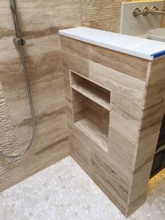 a bathroom with a stand up shower next to a white sink and tiled flooring