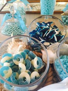 there are many different types of candies in bowls on the table with blue and white decorations