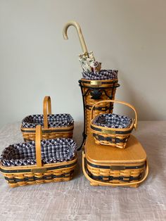 three pieces of woven luggage sitting on top of a white tablecloth covered floor next to an umbrella