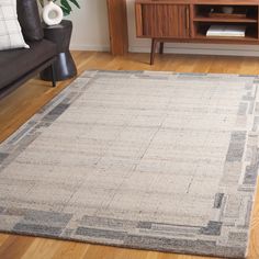 a living room area with a couch, coffee table and rug on the hardwood floor