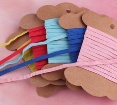 there are many different colored toothbrushes on the pink background with brown paper tags attached to them