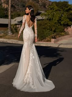 a woman in a wedding dress is standing on the street with her back to the camera