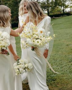 two women in white dresses are holding bouquets