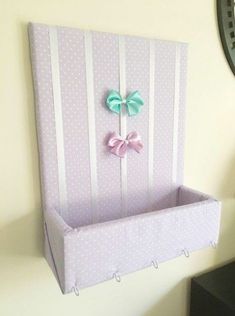 a pink and white striped box with bows on the top, hanging from a wall