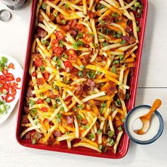 a casserole dish filled with cheese, bacon and tomatoes on a white table