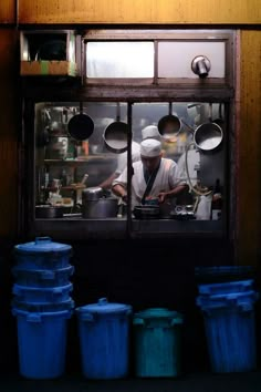 a man working in a kitchen behind several buckets