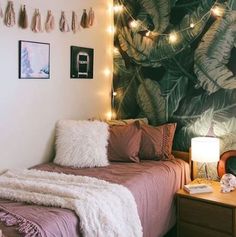 a bedroom decorated in pink and white with lights strung from the ceiling above the bed