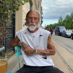 an older man with tattoos sitting at a table