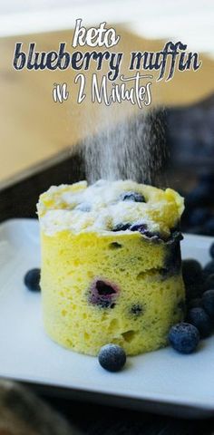 a blueberry muffin is sprinkled with powdered sugar on a white plate