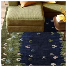 a living room area with a couch, coffee table and colorful rug on the floor