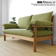 a green couch sitting on top of a hard wood floor next to a white wall