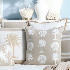 the pillows on the couch are decorated with palm trees and seashells in shades of beige