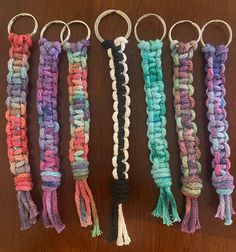 four different colored crochet key chains hanging on a table with one knot in the middle