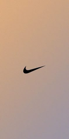 a black nike logo is seen in the sky at sunset or dawn with no clouds