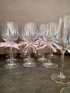 several wine glasses with pink bows are lined up in a row on a counter top