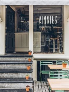 an outside view of a restaurant with tables and chairs on the steps leading up to it