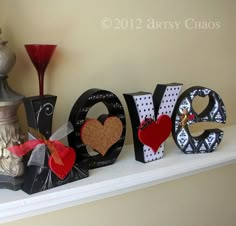 the word love is made out of paper and decorated with red bows, hearts, and other decorative items