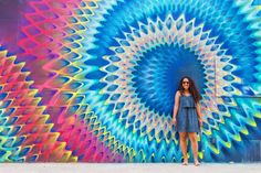 a woman standing in front of a colorful wall with an artistic design on the side