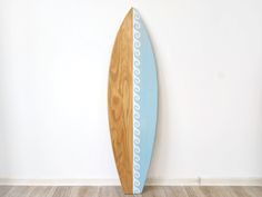 a wooden surfboard leaning up against a wall in a room with wood flooring