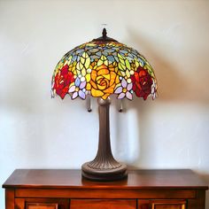 a stained glass lamp sitting on top of a wooden dresser next to a white wall