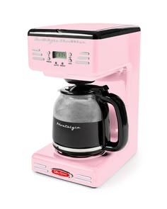 a pink coffee maker sitting on top of a white counter next to a black cup