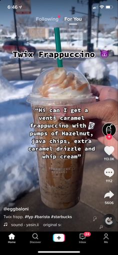 a person holding up a cup of coffee in front of snow covered ground and street signs