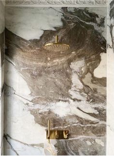 a bathroom with marble walls and flooring that looks like it has gold accents on the shower head