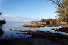 a lake surrounded by trees and rocks on a sunny day