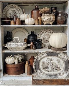 an old china cabinet filled with dishes and pumpkins