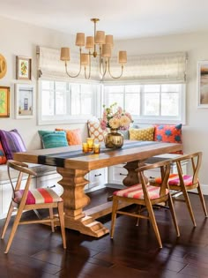 a dining room table with colorful pillows on it