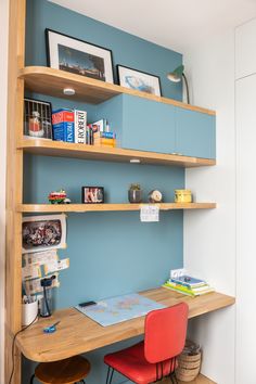 a desk and chair in a small room with blue walls, bookshelves and pictures on the wall