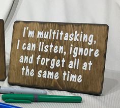 two wooden signs sitting on top of a table next to pen and marker holder with writing