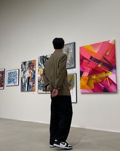 a man standing in front of paintings on the wall