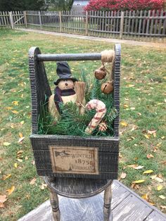 an old chair with stuffed animals in it on a wooden table outside next to grass and trees