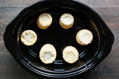 four pieces of banana sitting in a black crock pot on top of a wooden table