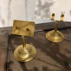 two brass candlesticks are on display in front of a white card holder and sign