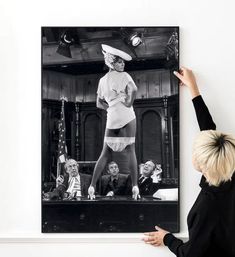 a woman standing in front of a black and white photo with her hands on the wall