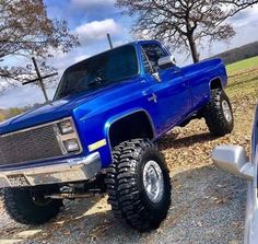 a large blue truck parked next to a white car