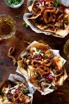 three plates filled with nachos sitting on top of a wooden table