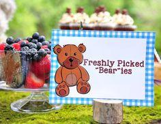 a teddy bear sitting next to a sign that says freshly picked berries on the table