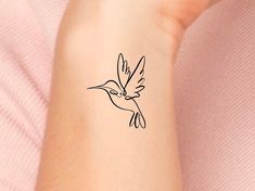 a small tattoo on the arm of a woman with a hummingbird in it's beak