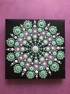 a painting on a purple background with green and pink circles in the center, surrounded by pearls