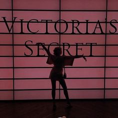 a woman standing in front of a wall with the words victoria's secret on it